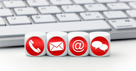 Contact us page concept with red and white icons on cubes in front of a keyboard