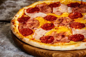 Pizza with ham and sausages on wood background