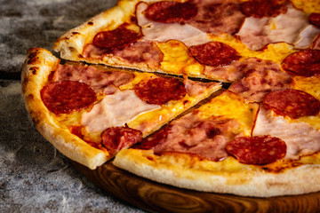 Pizza with ham and sausages on wood background
