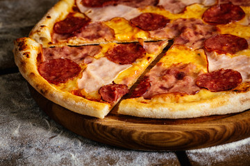 Pizza with ham and sausages on wood background