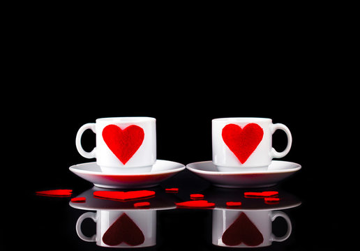 two cups of coffee on a black background and little red hearts for Valentine