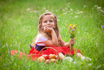 Obraz na płótnie Canvas Beautiful little girl picking flowers in a meadow