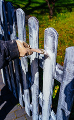 Painting fence. Hand holding paint brush