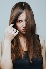 Fototapeta premium Studio shot of young beautiful brunette in black top posing and looking at camera on grey background. 
