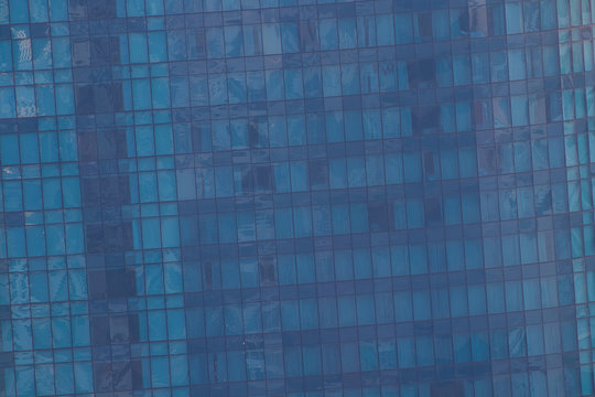 Windows of modern office building - architectural background. Toned in the blue color