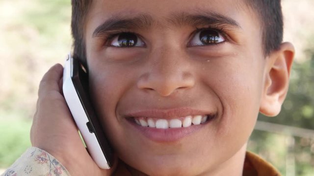Lovely little Indian boy talking on a cell phone mobile 