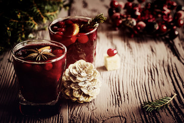 Christmas decoration and mulled wine with cranberries, anise and oranges. Dark wooden background, vintage effect, toned image.