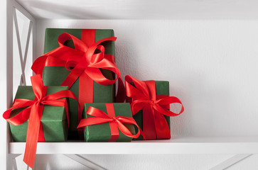 Holiday presents, gift boxes on white shelves at wall background