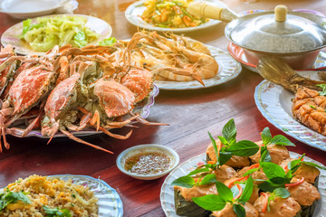 Thai style set of seafood insist of Thai steamed curry fish in banana leaf cups decorated with basil leaf, (Hor Mok Pla) steamed crab/prawn/shrimp with seafood sauce