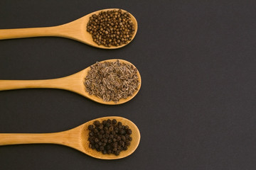 spices on bamboo spoons. coriander, black pepper, dill.