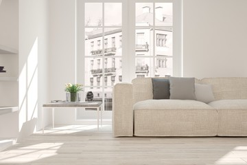 White room with sofa and urban landscape in window. Scandinavian interior design