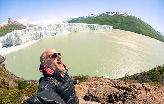 Young man solo traveler taking selfie at Perito Moreno glaciar in south american argentinian Patagonia - Adventure wanderlust concept on world famous nature wonder in Argentina - Warm turquoise filter