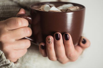 Brown cup with cocoa and marshmallow in the hands of the girl. M