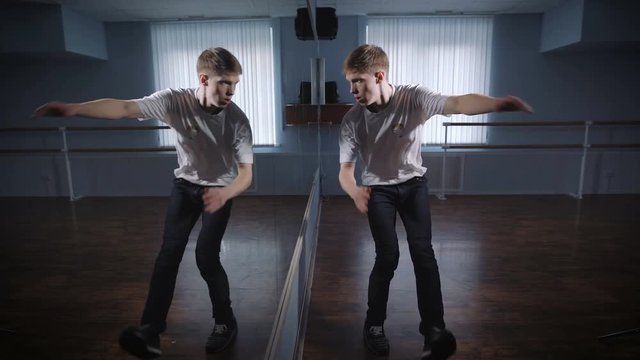 Young dancer hones moves standing in front of a large mirror in the dance studio. Well rehearsed hip hop dance. Stylish dance.