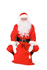 Santa Claus sitting on one's haunches with his sack,  isolated on white background. Full length portrait