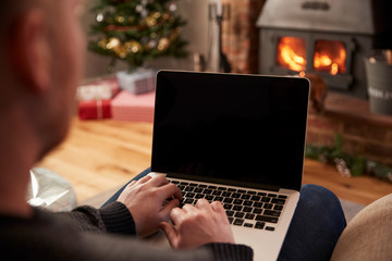 Man Using Laptop In Room Decorated For Christmas