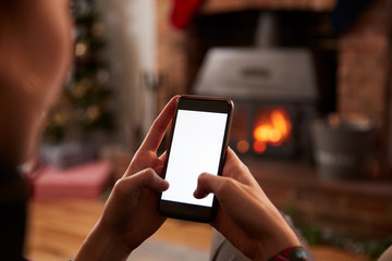 Man Using Mobile Phone In Room Decorated For Christmas