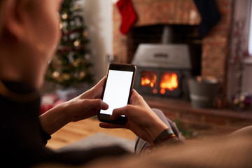 Man Using Mobile Phone In Room Decorated For Christmas