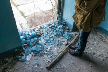 young boy stands in an abandoned building. wandering boy. man in a protective cloak with a hood. Post apocalypse. traveling on foot in a post-apocalyptic world.