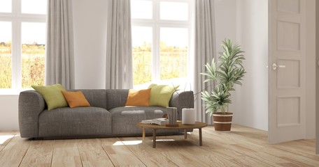 White room with sofa and autumn landscape in window. Scandinavian interior design