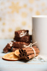 Chocolates with cup of hot drink, orange slices and cinnamon. Christmas Sweets with Soft focus background