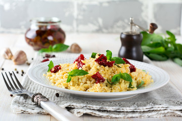 Bulgur with dried tomatoes and basil on a light wooden background. Vegetarian dish. Selective focus.