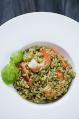 Closeup of spinach risotto with tomatoes and tiger shrimps