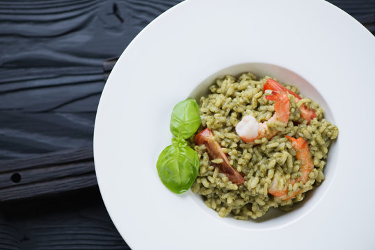 White glass plate with spinach and tiger shrimps risotto