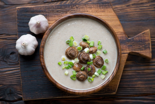 Bowl with champignon cream-soup on a rustic wooden surface