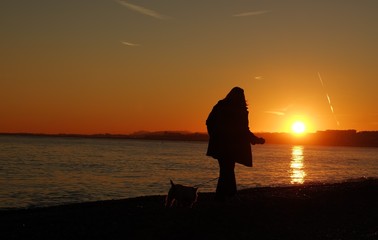 Woman walking the dog on the beach in Nice