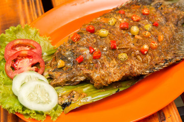 Grilled carp gourami fish with herbs tomatoes cucumber and chili pepper 