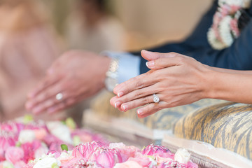 Hands pouring blessing water into bride's hands, Thai wedding ceremony.
