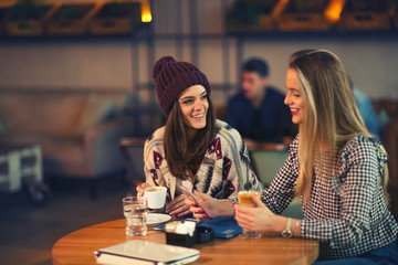 Two friends enjoying coffee together in a coffee shop as they si