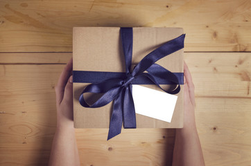 Female hands holding gift box with blank gift tag 