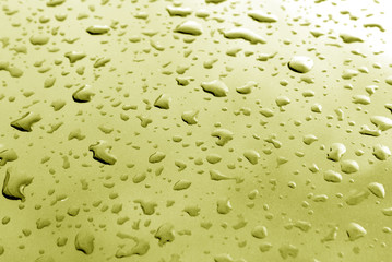Rain drops on yellow metal surface with blur effect
