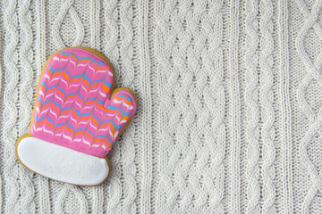 Ginger cookie mitten on white knitted background