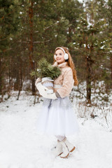 Attractive young girl in wintertime outdoor. A girl in the winter forest smiling and cheering.  Snow is falling