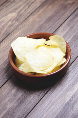 A dish with chips standing on dark gray colored wooden table. Vertical studio shot