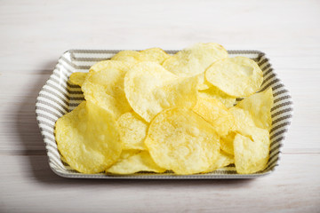 Server with chips standing on pale gray wooden table. Horizontal studio shot