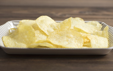 Server with chips standing on  wooden table. Horizontal studio shot