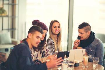 Group of young people sitting in a coffee shop having fun