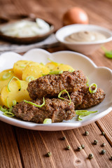 Cevapcici made of minced meat with potato, leek and onion