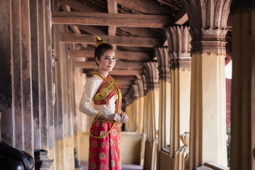 Asian woman in Laos traditional dress standing in temple.