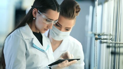 Young scientists with tablet pc making test or research in clinical laboratory - Powered by Adobe