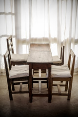 Fototapeta na wymiar White room with wooden table and chair in light of sunset