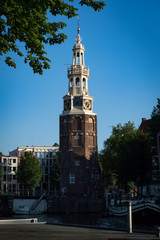 Fototapeta na wymiar The 1606 Montelbaanstoren tower on bank of the canal Oudeschans in Amsterdam, Netherlands. The original tower was built in 1516 as part of the Walls of Amsterdam.