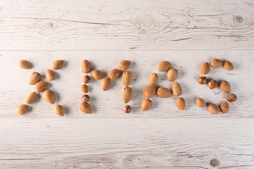 Wrote XMAS text with almond on wooden background