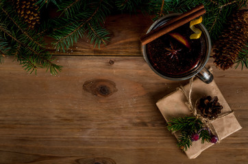 Traditional Christmas drink mulled wine, next to the Christmas tree branches, presents and decorations, copy space top view