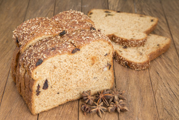 Slices of bread with whole raisins on the wooden background