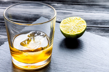 rum with ice in glass on dark background and lime